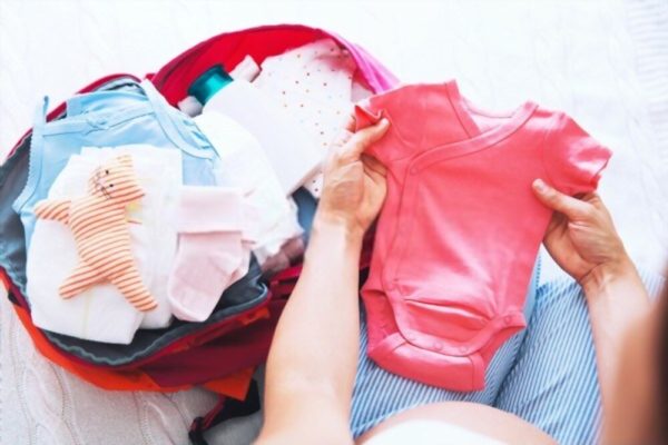 Image showing pregnant mother packing clothes for baby